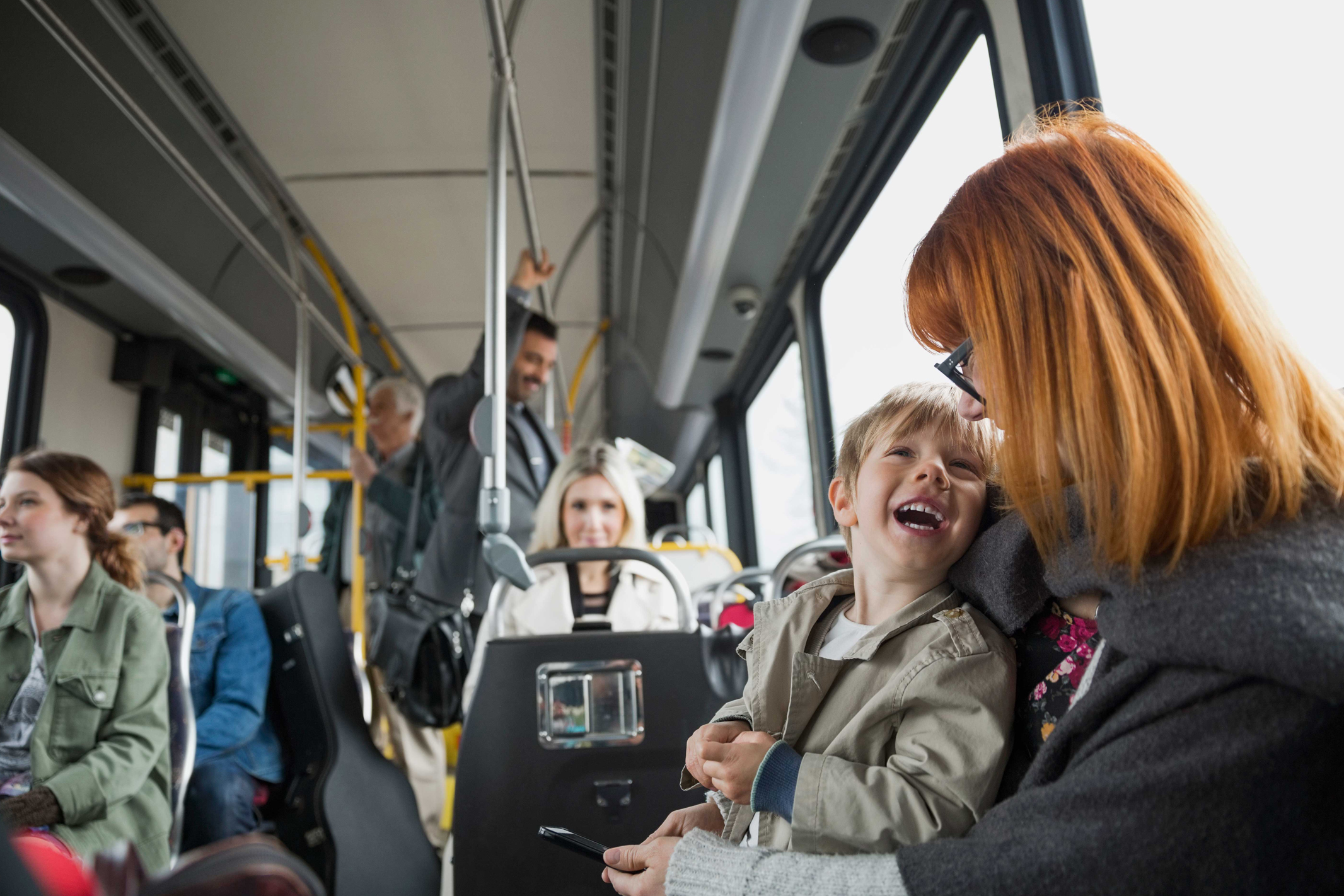 Mom and son smiling on a bus